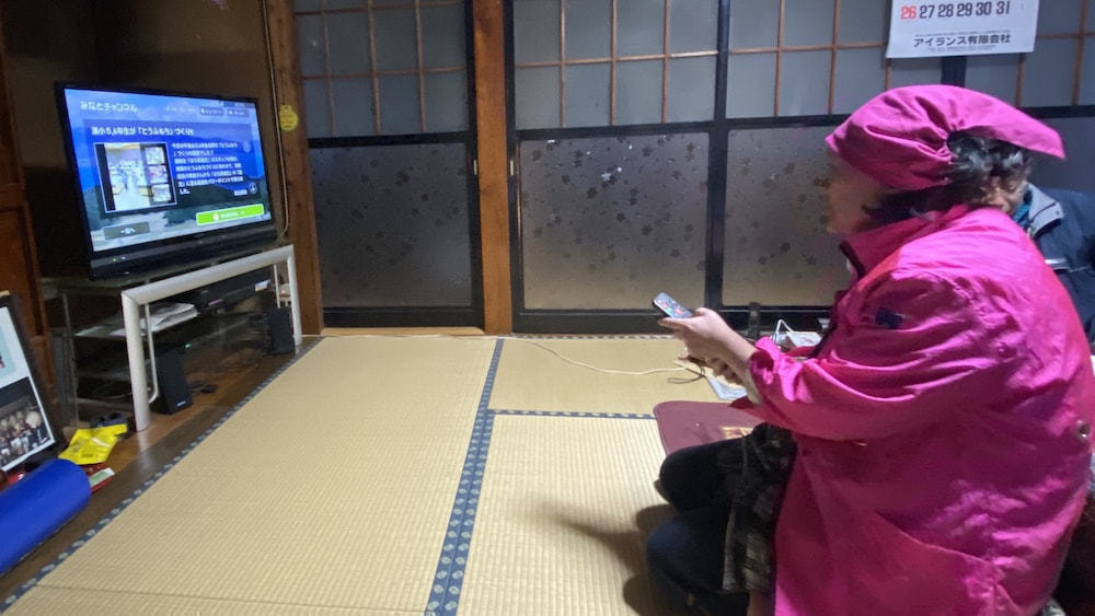 テレビを操作する高齢者